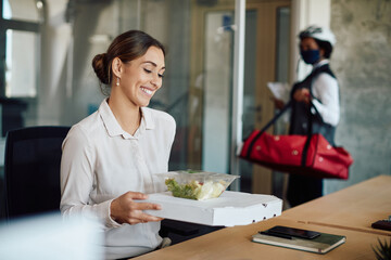 Happy businesswoman with lunch delivered by food courier at the office.