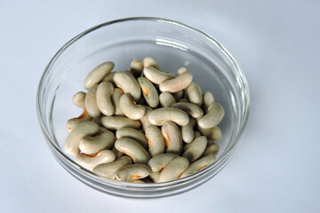 Dry light brown beans in a glass bowl, white background
