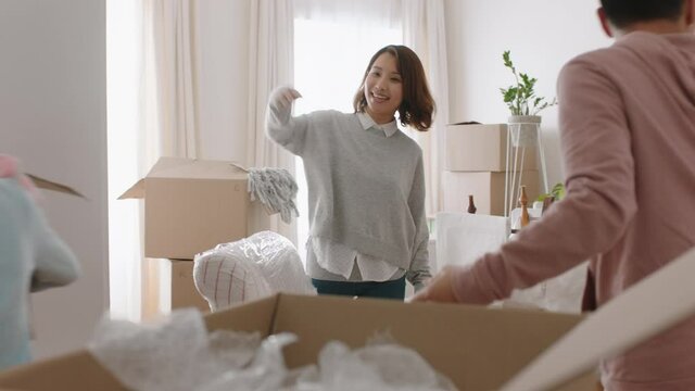 happy asian family moving into new home owners with children helping parents move into house carrying boxes enjoying teamwork together with kids real estate property investment 4k footage