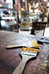 Paint brushes on old weathered table top in antique rustic looking shophouse