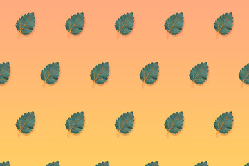 Green leaves forming a pattern on an orange background, autumn season concept