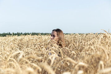 Young woman in a field of wheat golden field of ripe wheat
