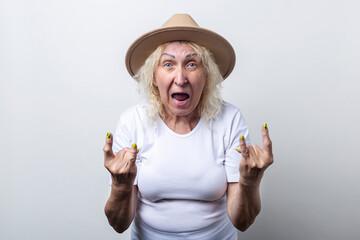 Old woman in a hat shows a rocker horn gesture on a light background