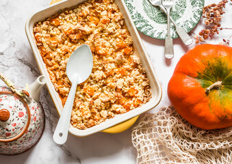 Delicious autumn dessert - pumpkin crumble in baking tray on a marble background, top view