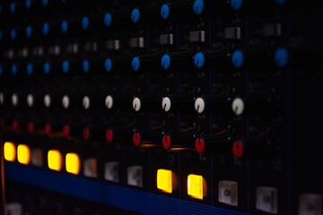 Sound mixer control panel on dark light background in audio control room.