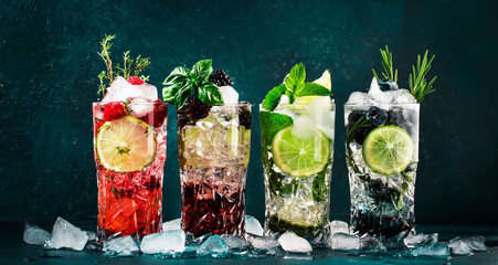 Fototapeta na wymiar Cocktails drinks. Classic alcoholic long drink or mocktail highballs with berries, lime, herbs and ice on blue background
