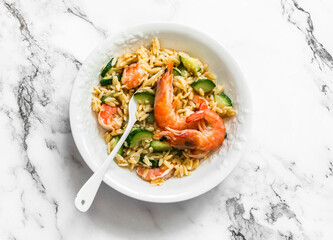 Delicious mediterranean lunch - creamy orzotto with shrimp and zucchini on a marble table, top view