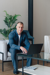 Businessman sitting in an office working with a laptop computer. Business man portrait.