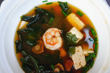soup with shrimp, algae, mushrooms and tofu cheese in a white plate. top view.