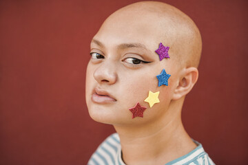 Bald girl wearing stars stickers with red background - Real people, diversity and female power...