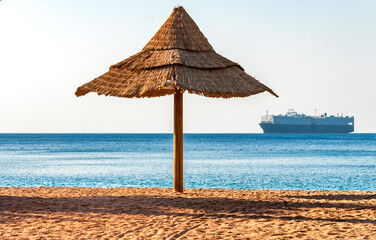 Lonely umbrella on sandy beach of the Red Sea. It is waiting for vacationers from all around of the world
