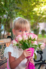 Cute schoolgirl with a bouquet of roses. Primary school student. School holiday.