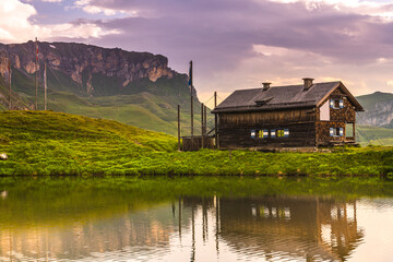 Obraz premium Wooden Cabin Hut at Lake in High Alpine Mountains in Summer Sunrise