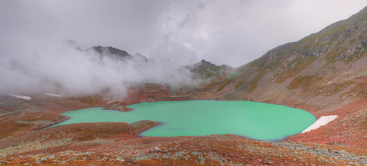 A beautiful mountain lake. A cloud hangs over the lake. Lake Geybashkol in the Republic of Kabardino-Balkaria, Russia.