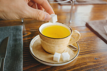 A man puts white refined sugar in green herbal tea. The concept of diabetes and addiction to fast carbohydrates