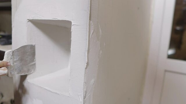 woman putty plaster on drywall, interior renovation