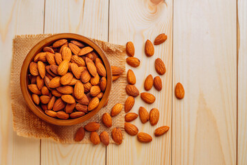 Top view of almonds on a wooden table Almonds in a wooden bowl The nuts are freely placed on the dark board.