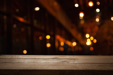 blurred cafe background, reflections of bokeh light bulbs, restaurant bar and dark brown wooden work table in retro style.