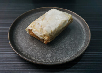 baked handmade paper wrapped chicken meat with herbal dark soy sauce on dark grey wood background dim sum menu