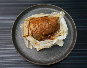 baked handmade paper wrapped chicken meat with herbal dark soy sauce on dark grey wood background dim sum menu