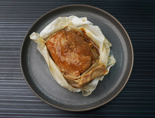 baked handmade paper wrapped chicken meat with herbal dark soy sauce on dark grey wood background dim sum menu