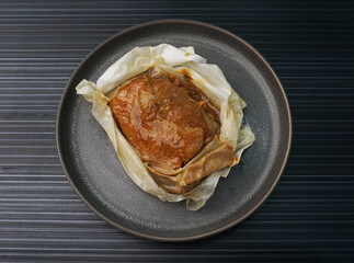 baked handmade paper wrapped chicken meat with herbal dark soy sauce on dark grey wood background dim sum menu
