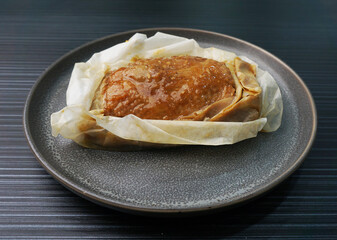 baked handmade paper wrapped chicken meat with herbal dark soy sauce on dark grey wood background dim sum menu