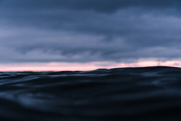 Cloudy sunset over the dark ocean with a bright stripe over the horizon