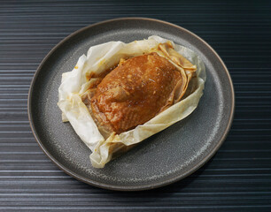 baked handmade paper wrapped chicken meat with herbal dark soy sauce on dark grey wood background dim sum menu