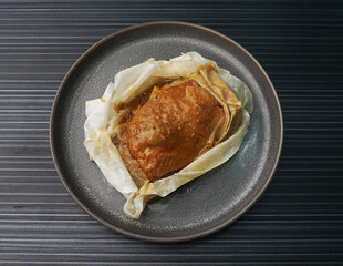baked handmade paper wrapped chicken meat with herbal dark soy sauce on dark grey wood background dim sum menu
