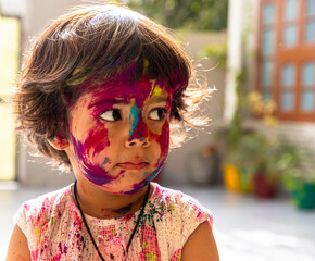 colorful portrait of cute indian baby girl during holi festival.