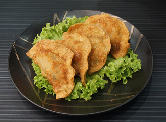 handmade deep fried and boiled pork meat dumpling wanton soup in plate on dark grey wood table asian dim sum halal food restaurant cuisine banquet menu for cafe