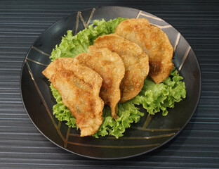 handmade deep fried and boiled pork meat dumpling wanton soup in plate on dark grey wood table asian dim sum halal food restaurant cuisine banquet menu for cafe