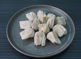 handmade deep fried and boiled pork meat dumpling wanton soup frozen raw product in plate on dark grey wood table asian dim sum halal food restaurant cuisine banquet menu for cafe