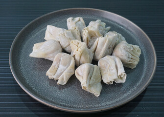 handmade deep fried and boiled pork meat dumpling wanton soup in plate on dark grey wood table asian dim sum halal food restaurant cuisine banquet menu for cafe