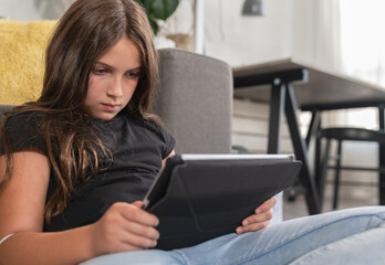Fototapeta na wymiar Teenage Girl Studying At Home While Watching Online Classes On Smartphone