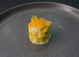 classic steamed fresh yellow stew mai dumpling wrapped with pork and fish roe caviar on dark grey wood background dim sum menu