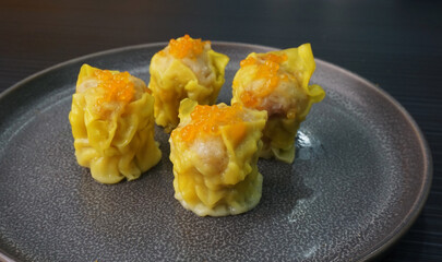 classic steamed fresh yellow stew mai dumpling wrapped with pork and fish roe caviar on dark grey wood background dim sum menu