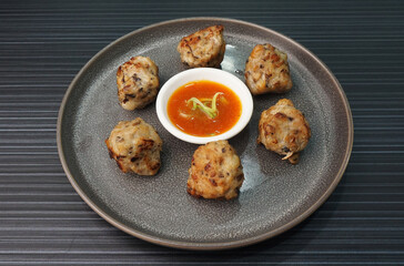 deep fried pork meatball with scallop and mushroom and chilli dip on dark grey wood background dim sum menu