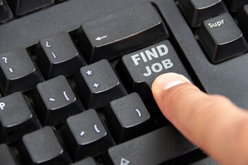 Close-up of a finger pressing the search job key on a laptop keyboard
