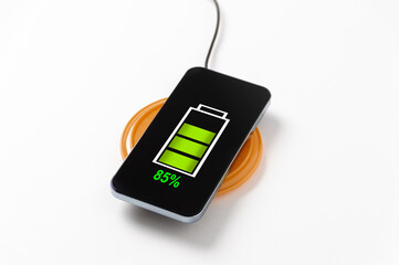 Close up of wireless charging of modern black glossy metal touchscreen smartphone on wireless power...