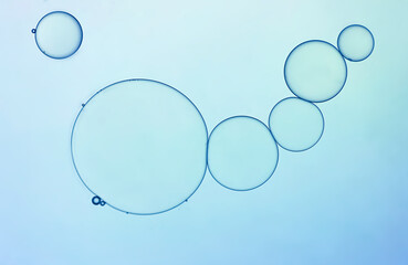 Abstract oil droplets create shapes and pattern on light blue  backgrounds.