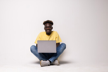 serious young man using a laptop sitting on the floor.