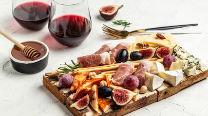Assortment of cheese with wine, honey, nuts and grape on cutting board. Cheese platter. Appetizers