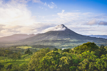 Fototapeta premium Tropical landscape with a volcano rolled by a cloud