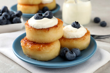 Delicious cottage cheese pancakes with blueberries, honey and sour cream on light table, closeup