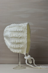 boutique baby bonnet - hand knitting displayed on a glass stand 