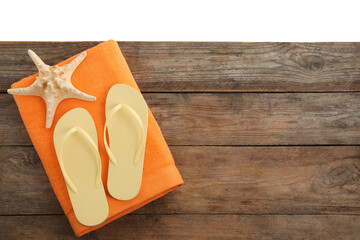 Wooden surface with beach towel, starfish and flip flops on white background, top view. Space for text