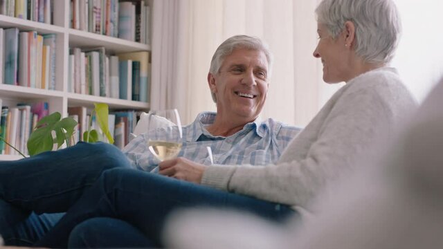 happy old couple drinking wine relaxing on sofa at home making toast celebrating anniversary enjoying romantic relationship on comfortable retirement 4k footage