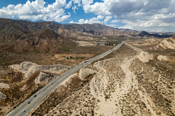 scenic aerial landscape of mountains blue skies clouds and highway in desert